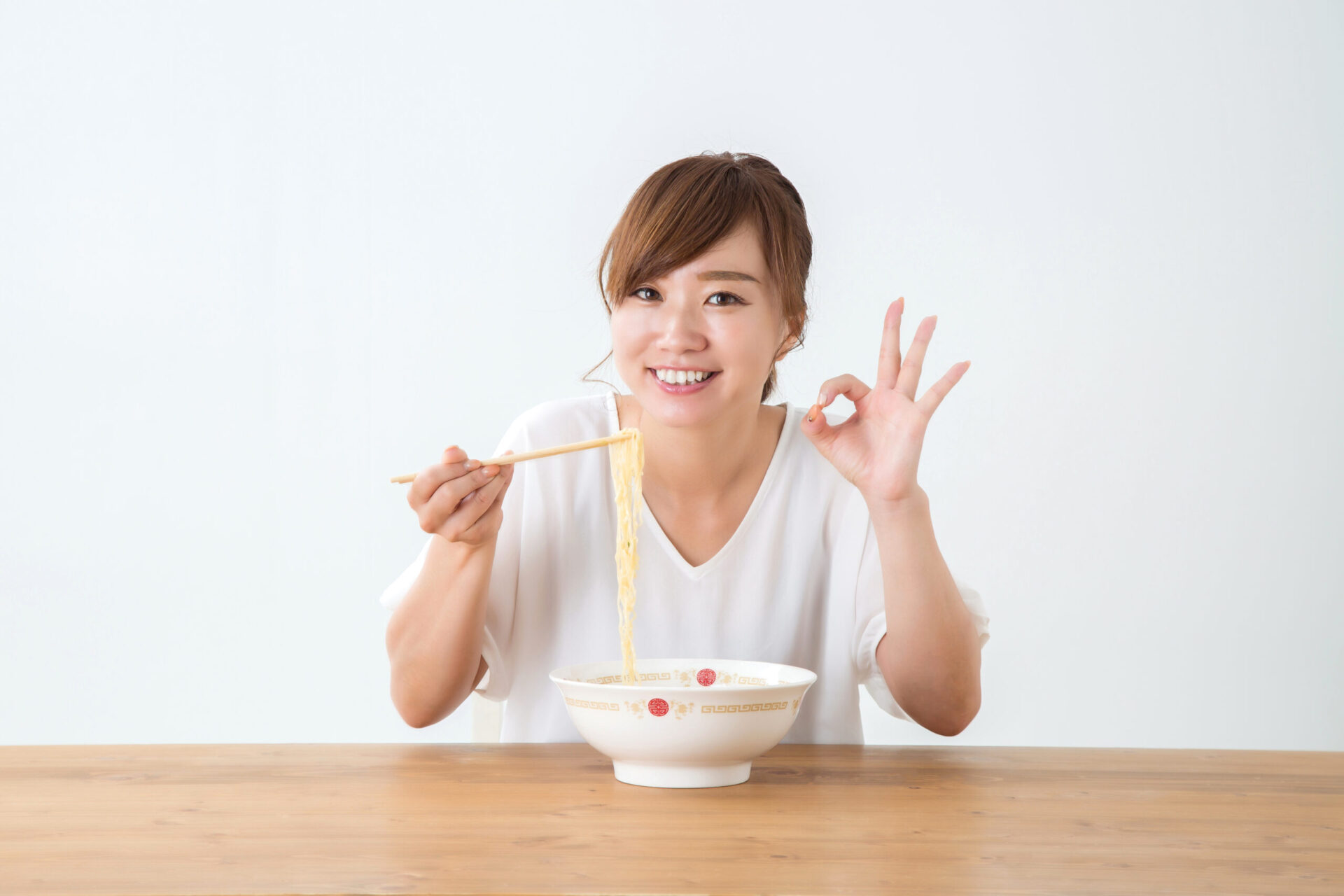 うどんを食べながらOKサインを出す女性