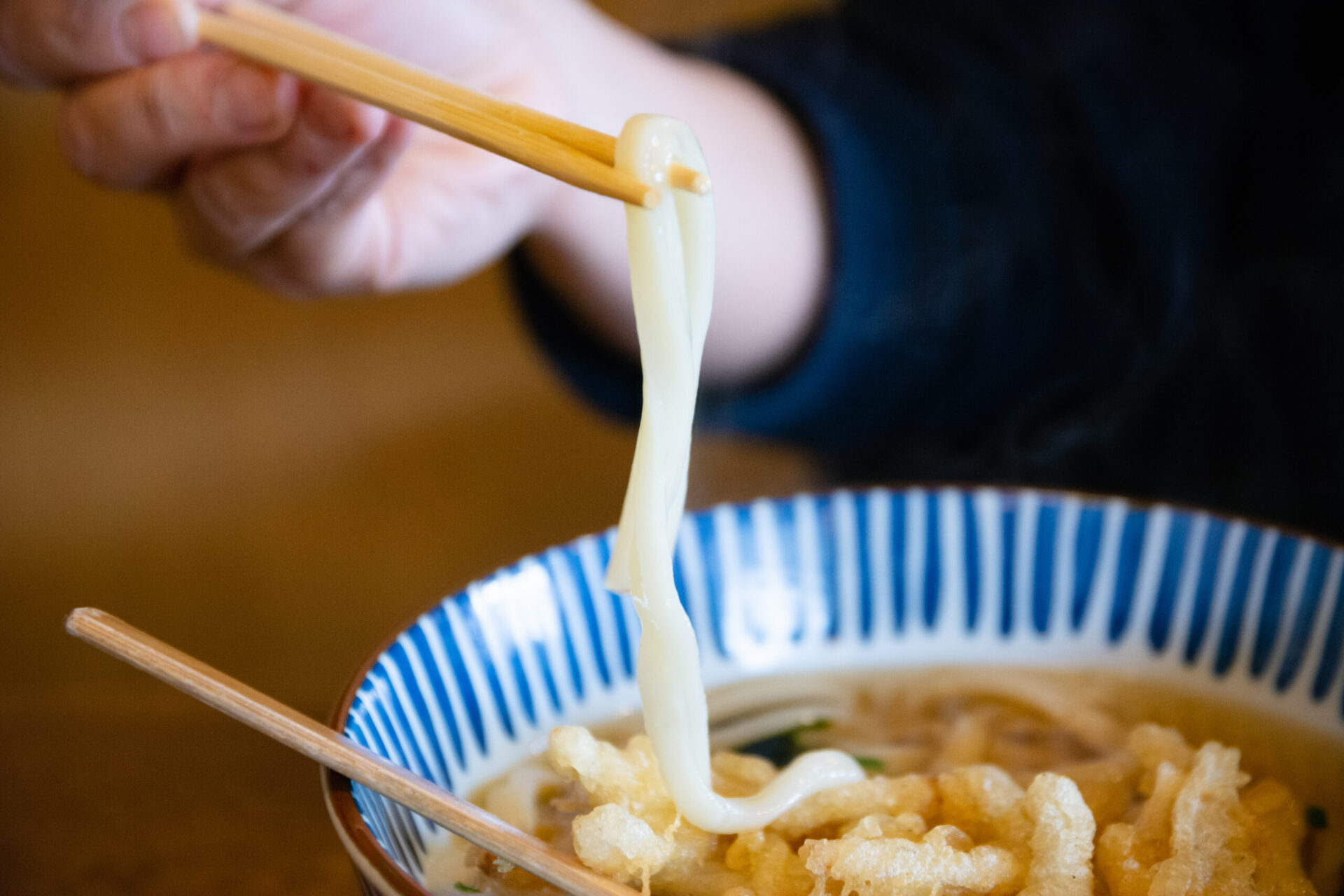 うどんを箸上げする男性の手