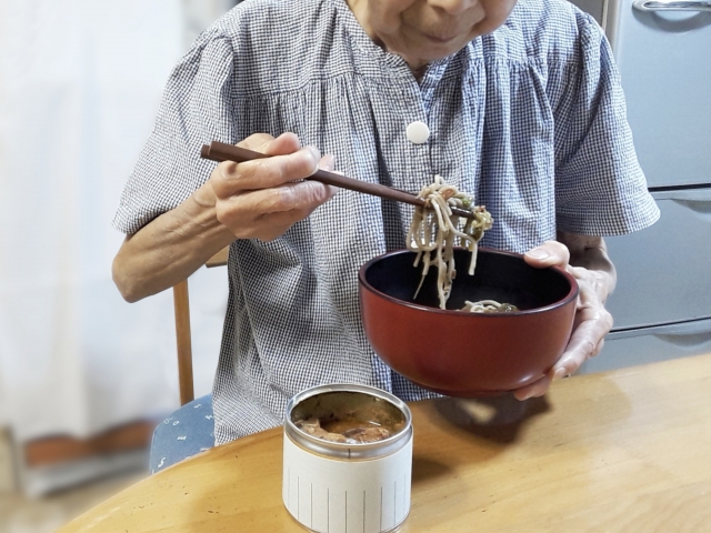 食べやすい長さに切られた麺類を食べる高齢者